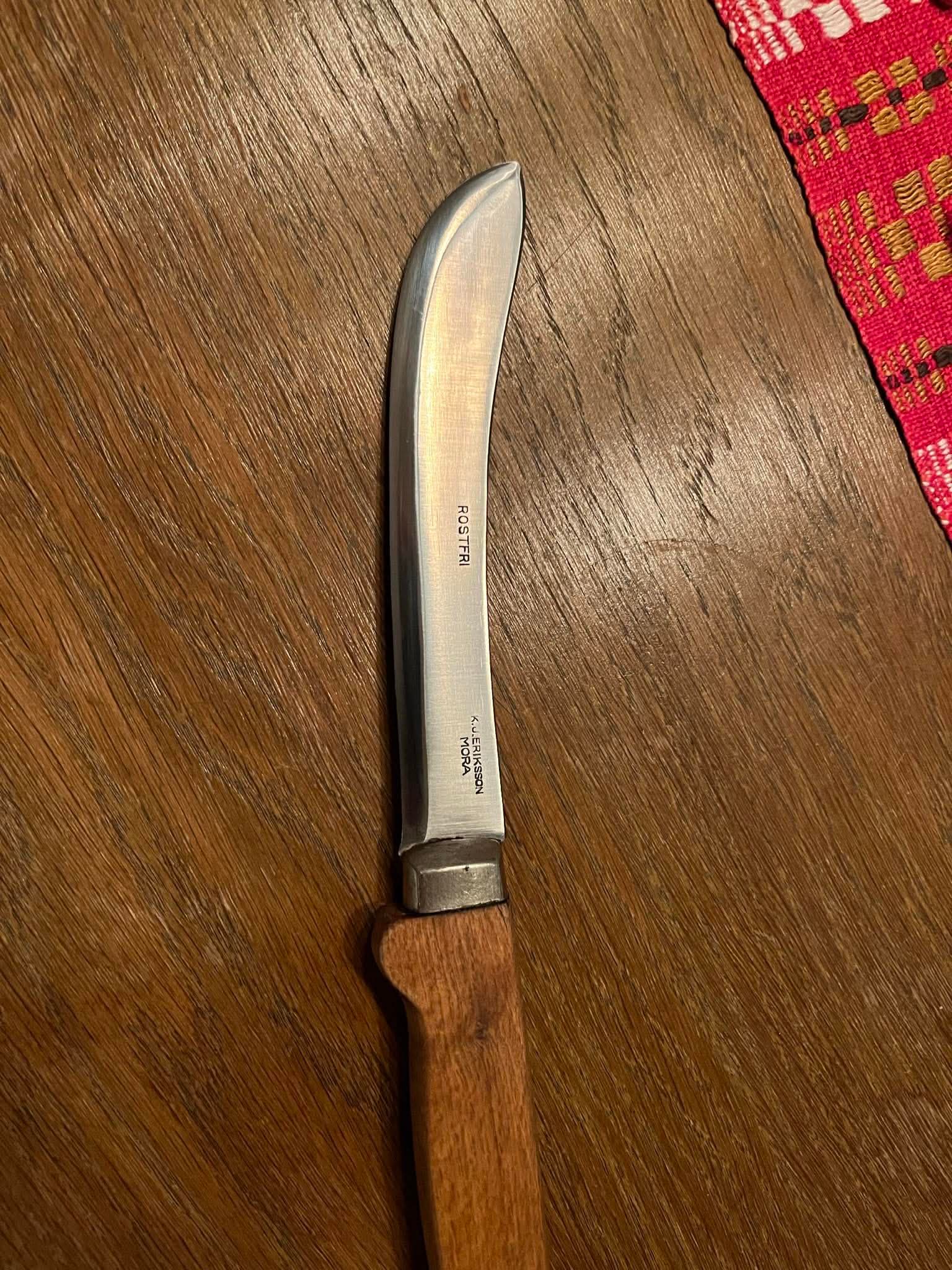 Styckarkniv med träskaft på mörkt bord, röd bordsduk i kanten