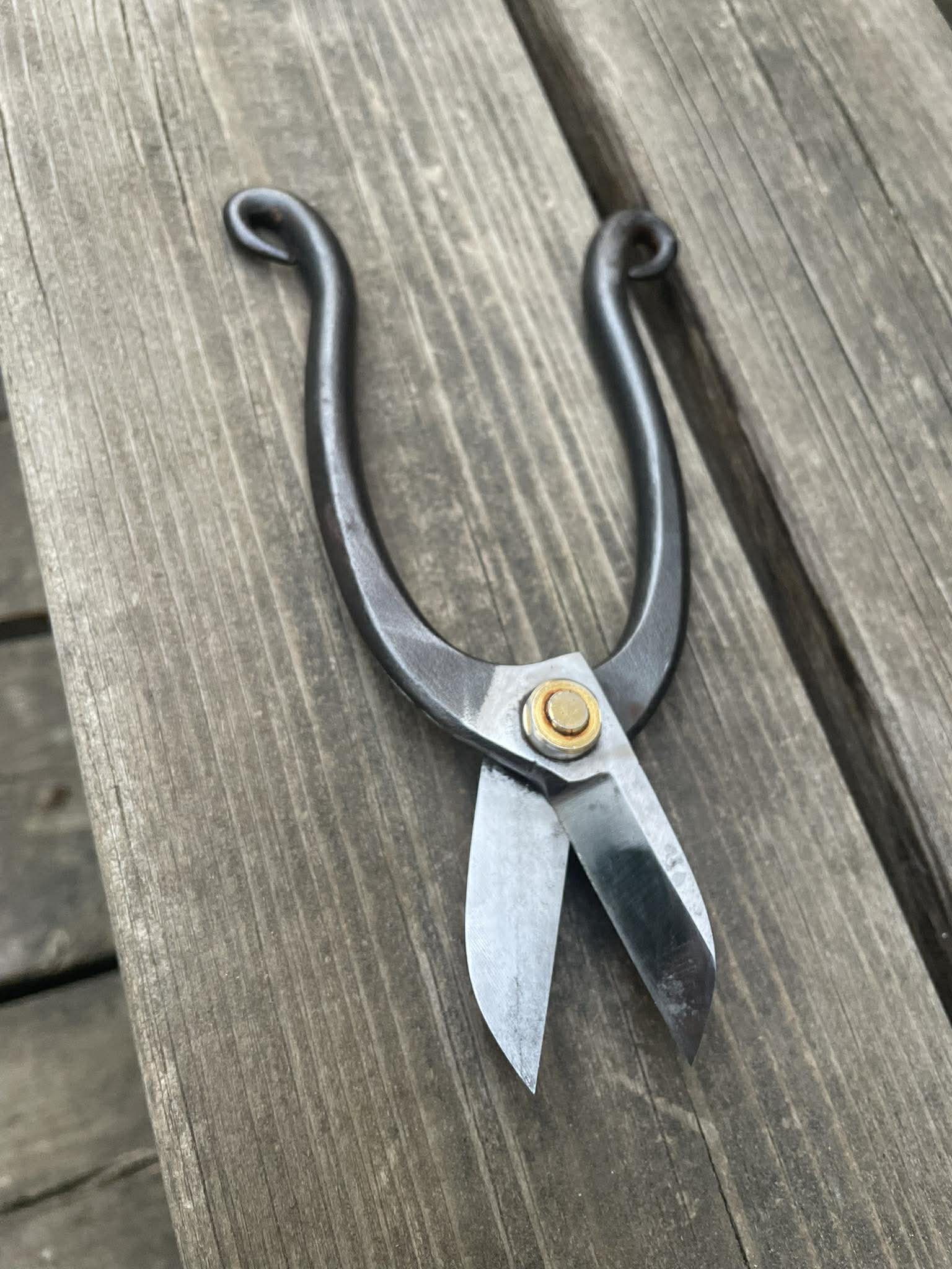 Handsmidd sax med polerade eggar och mörk patina på träbord